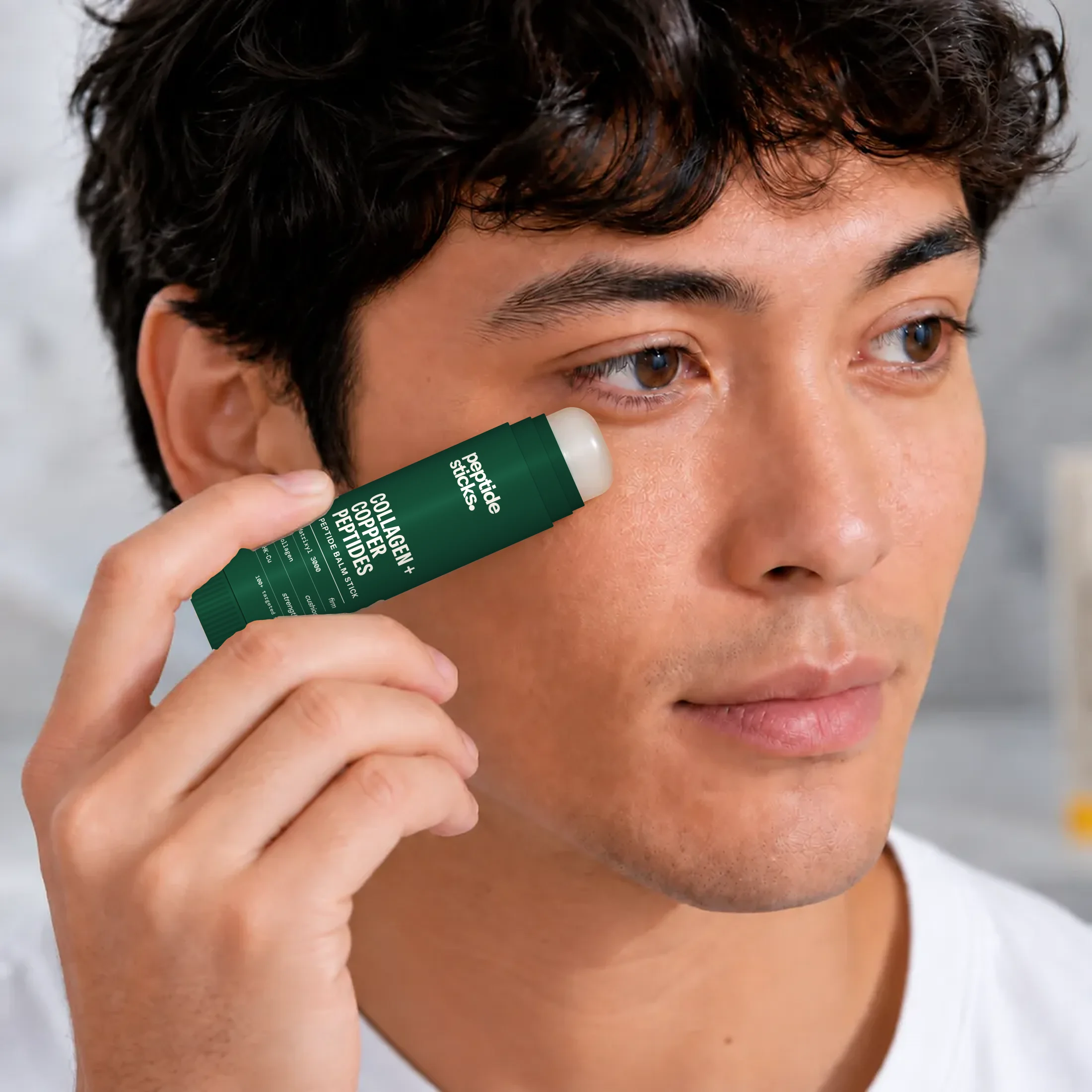 A man applying the Collagen + Copper Stick to his cheek