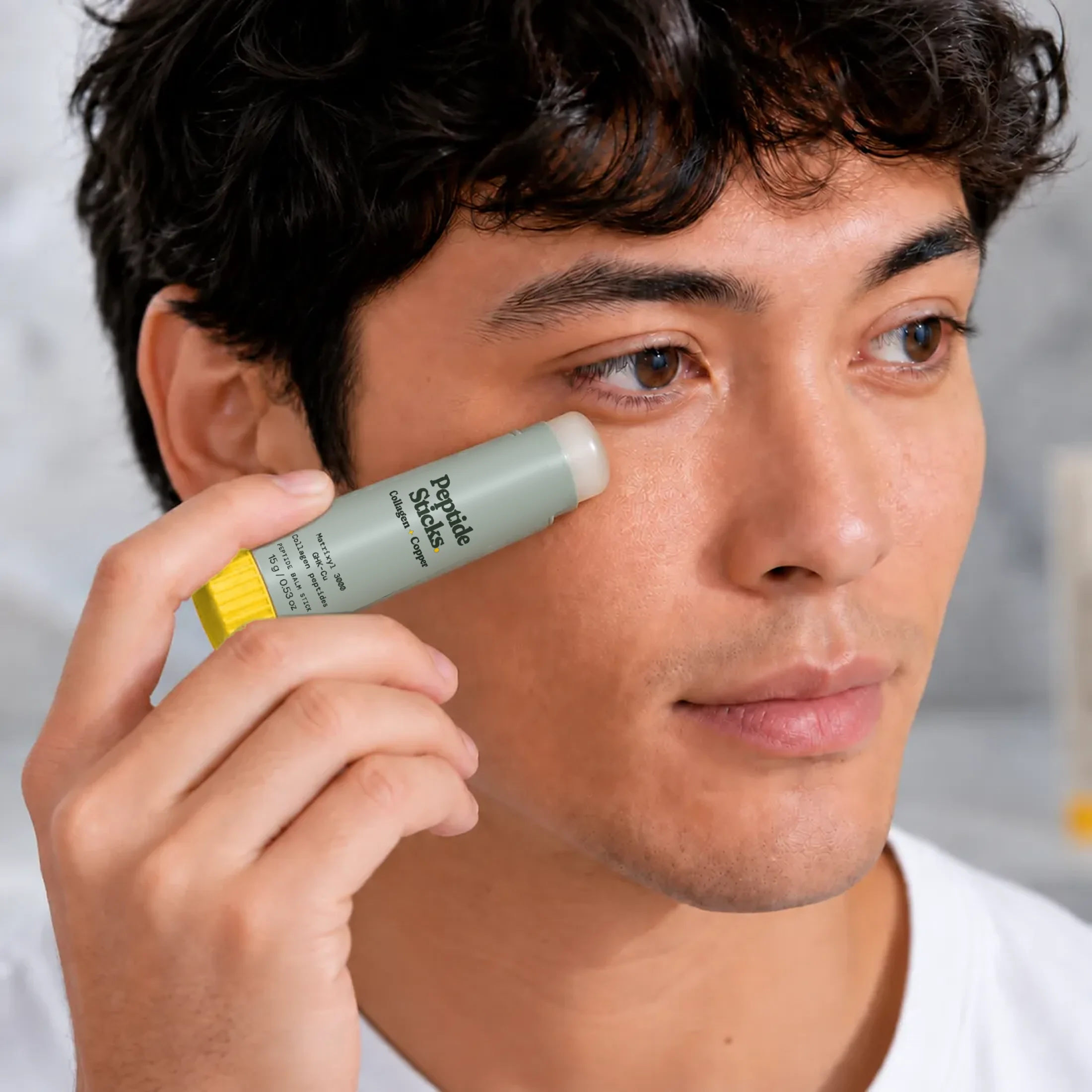 A man applying the Collagen + Copper Stick to his cheek